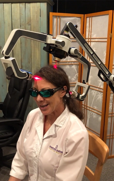 A woman is undergoing regenerative therapy with a machine attached to her head.